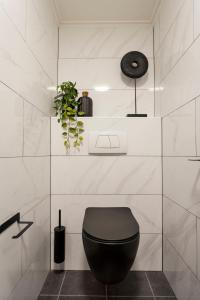 een badkamer met een zwart toilet in een witte muur bij 't Hoekje in Enschede