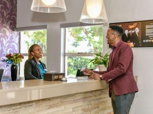 a man and a woman standing at a cash register at Mercure Hotel Bedfordview in Johannesburg