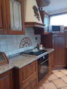 uma cozinha com armários de madeira e um forno com placa de fogão em CASA FILAFERRO - VIA LOMBARDIA 4 MOGGIO UDINESE em Moggio Udinese