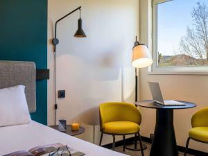 ein Hotelzimmer mit einem Bett und einem Laptop auf einem Tisch in der Unterkunft Ibis Barcelona Aeropuerto Viladecans in Viladecáns