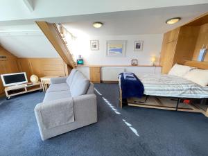 a bedroom with a bed and a couch and a tv at Crows Nest - panoramic views of St Ives harbour in St Ives