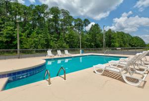 a swimming pool with lounge chairs and a volley ball court at Super 8 by Wyndham Diberville Biloxi Area in Biloxi