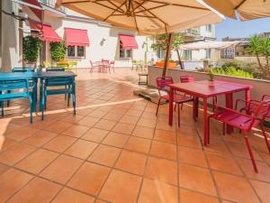 un patio esterno con tavoli, sedie e ombrelloni di Ibis Styles Napoli Garibaldi a Napoli