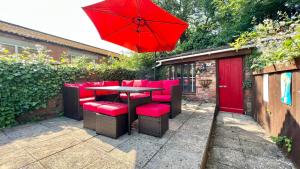 惠靈頓的住宿－3 Bedroom Character Townhouse on Edge of Blackdown Hills，一张桌子、红色的椅子和红色的雨伞