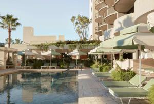 uma piscina com cadeiras e guarda-sóis ao lado de um edifício em The Calile Hotel em Brisbane