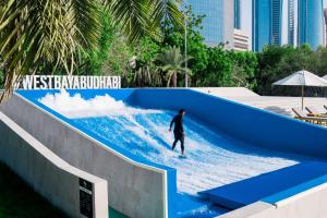 Un uomo che cavalca un'onda su una tavola da surf in una piscina di onde di Radisson Blu Hotel & Resort, Abu Dhabi Corniche a Abu Dhabi