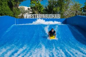 a man riding a wave on a water slide at Radisson Blu Hotel & Resort, Abu Dhabi Corniche in Abu Dhabi