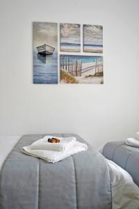 a bed with a towel and three paintings on the wall at Electra apartment Agia Triada in Agia Triada
