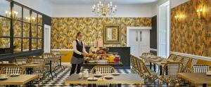 a woman standing in a restaurant with a tray of food at Summerhill House Hotel in Enniskerry