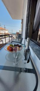 a table with two wine glasses and a plate of fruit at Electra apartment Agia Triada in Agia Triada