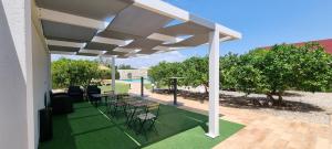 eine Terrasse mit einem Tisch und Stühlen unter einer Pergola in der Unterkunft Quinta dos I's - Algarve in Algoz