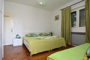 a bedroom with a bed with yellow sheets and a green blanket at Apartments Silvija near Luke beach in Murter