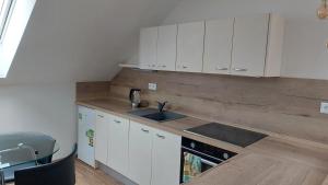 a kitchen with white cabinets and a sink at Southfork u Štěpánků - Apartmán Branišov 