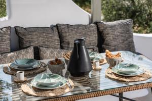 uma mesa de vidro com pratos e tigelas de comida em Arsenis Luxury Villas em Plaka