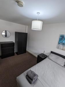 um quarto com uma cama branca, uma cómoda e uma mesa de cabeceira em Self contained town house in Mexborough em Mexborough