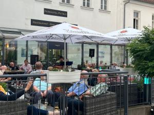 grupa ludzi siedzących w fotelach pod parasolami w obiekcie Parkhotel Putbus Superior International w mieście Putbus