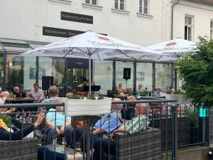 eine Gruppe von Personen, die unter Sonnenschirmen auf Stühlen sitzen in der Unterkunft Parkhotel Putbus Superior International in Putbus