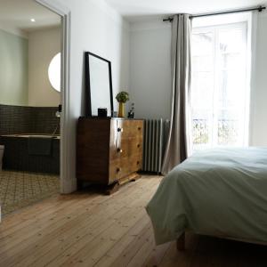 Schlafzimmer mit einem Bett, einem Spiegel und einer Badewanne in der Unterkunft Chambres d'hôtes Les Pergolas in Marcigny