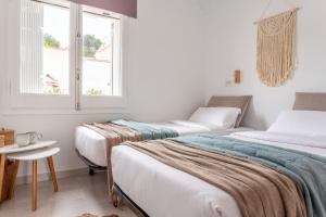 a room with two beds and a table and two windows at Apartamento Bohemia in L'Escala