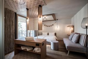um quarto com uma cama e um sofá em Hotel Tofana em San Cassiano