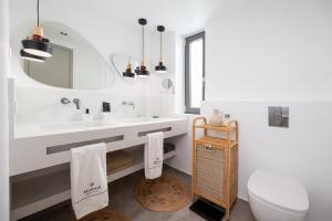 a bathroom with a sink and a toilet and a mirror at Mnḗmē Suites & Villas in Kastrí