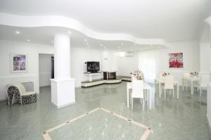 佩斯基奇Vacanze Top的白色的客房配有桌椅和电视。