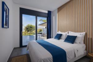 a bedroom with a large bed with blue and white pillows at Kali Thea Villas in Hersonissos