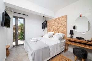 a white bedroom with a bed and a mirror at Mnḗmē Suites & Villas in Kastrí
