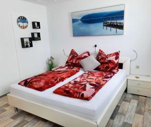uma cama com edredão vermelho e almofadas em Ferienhaus Arnhof em Heidenreichstein