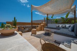 a patio with a couch and chairs and the ocean at Mnḗmē Suites & Villas in Kastrí +37 photos