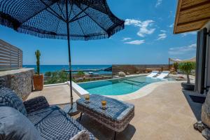 a patio with a table and an umbrella and a swimming pool at Mnḗmē Suites & Villas in Kastrí