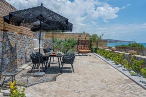 a patio with a table and chairs and an umbrella at Mnḗmē Suites & Villas in Kastrí