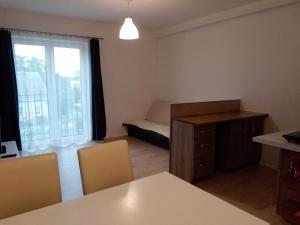 um quarto com uma mesa e cadeiras, uma cama e uma janela em Apartamenty 3D em Giżycko