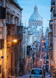 a car driving down a city street with a dome at Valletta Stylish City Pad in Valletta