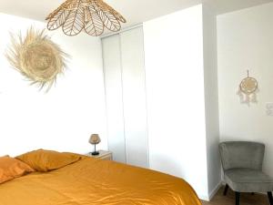 ein Schlafzimmer mit einem Bett, einem Stuhl und einem Kronleuchter in der Unterkunft La Terrasse du SloI - Proche plage in Notre-Dame-de-Monts