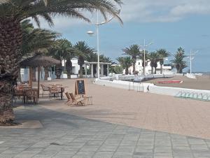 a beach with tables and chairs and palm trees at Sol y terraza in Playa Honda