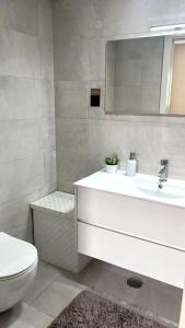 een badkamer met een wastafel, een toilet en een spiegel bij Flat moderno e central em Braga in Braga