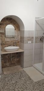 y baño de piedra con lavabo y ducha. en Casa di Sissi en Monterosso Almo
