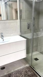 a bathroom with a white sink and a shower at Flat moderno e central em Braga in Braga