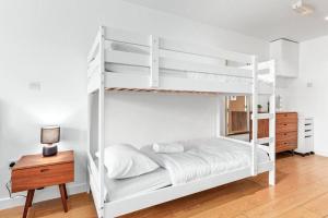 een slaapkamer met witte stapelbedden en een houten tafel bij Sleep6 In Leicester Square, Soho VR7 in Londen