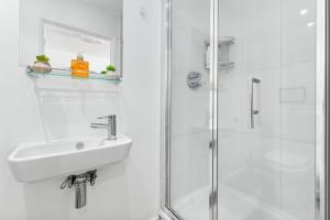 a white bathroom with a sink and a shower at Sleep6 In Leicester Square, Soho VR7 in London