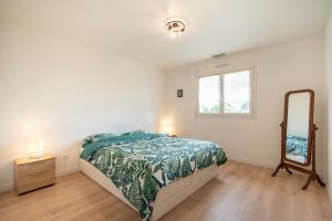 1 dormitorio con cama, tocador y espejo en Entre lacs & Océan - Maison climatisée avec jardin, en Vielle-Saint-Girons