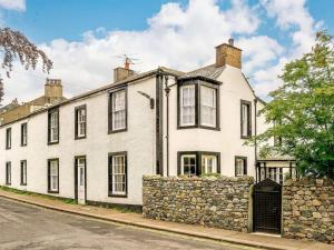 a large white house with a stone wall at Oak Lodge in Keswick