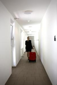 a woman walking down a hallway with a red suitcase at Arbio I Urbanstay Serviced Studios & Apartments in Graz