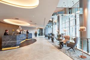 a lobby with chairs and a bar in a building at Steigenberger Hotel Hamburg in Hamburg