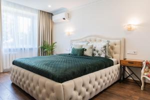 a bedroom with a large bed with a green comforter at E. D. Elite Apartment in Šiauliai