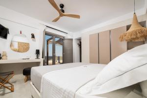 a white bedroom with a bed and a desk at Mnḗmē Suites & Villas in Kastrí