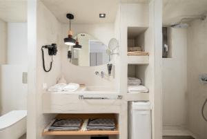 a white bathroom with a sink and a mirror at Mnḗmē Suites & Villas in Kastrí