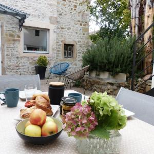 una mesa con un bol de frutas y flores en ella en Chambres d'Hôtes Les Pergolas, en Marcigny