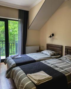two beds in a room with a window at Hotel Gold Kazbegi in Stepantsminda